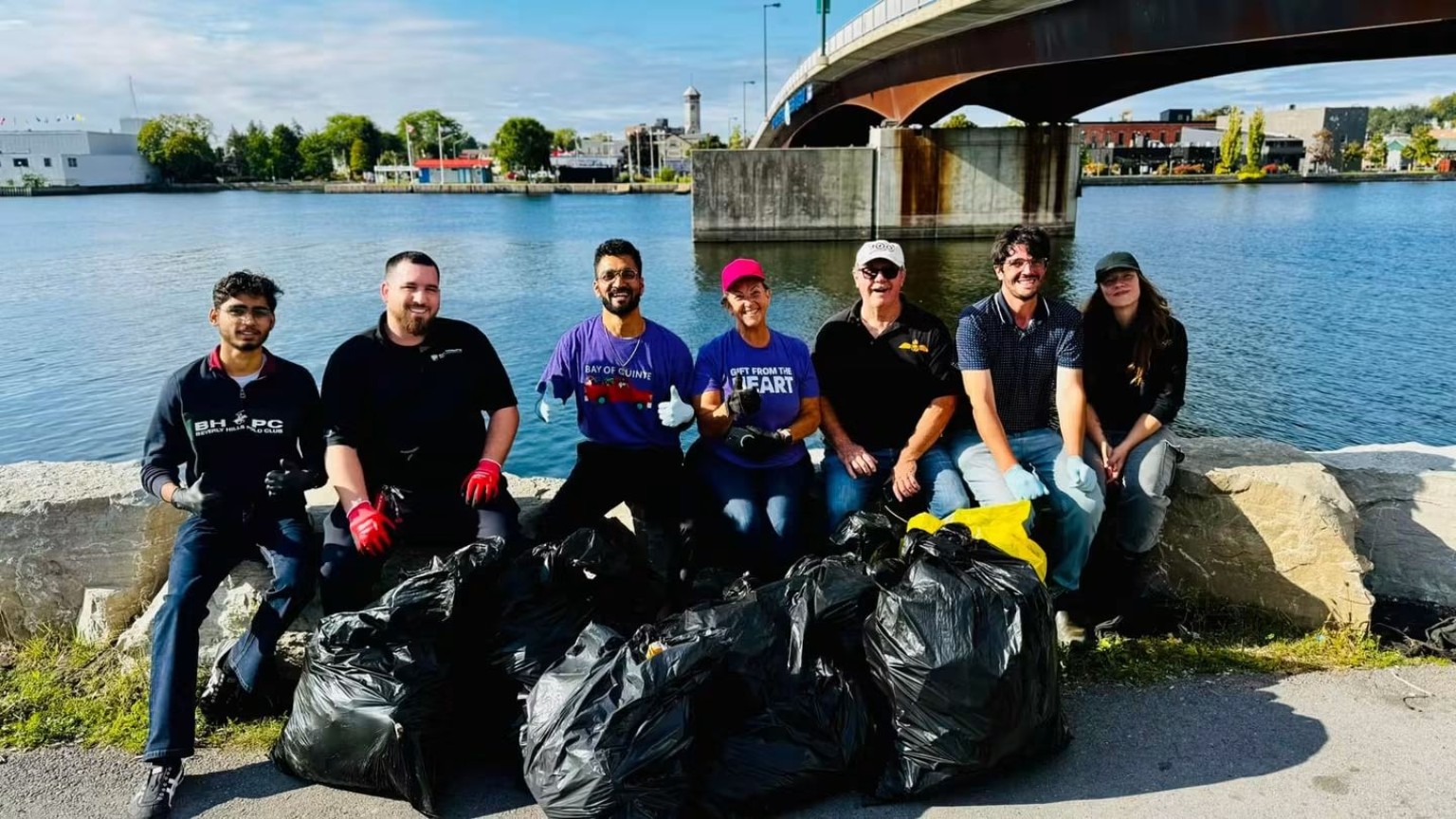 Community cleanup volunteers with collected rubbish beside the Trent River