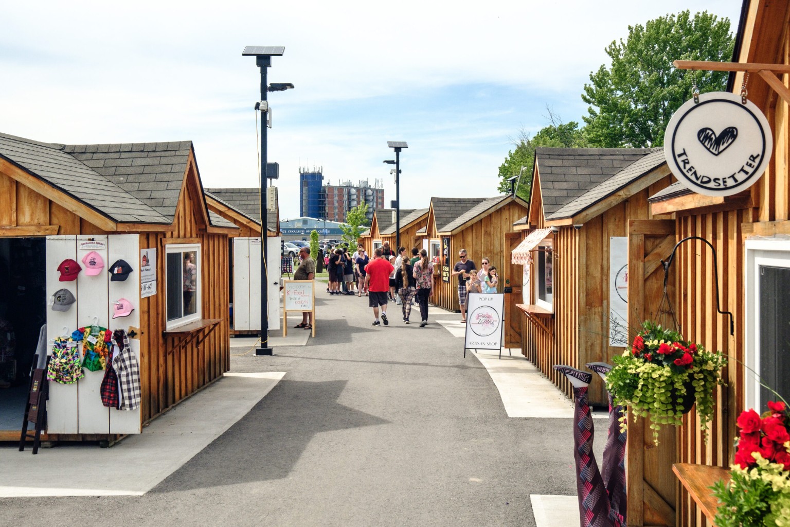 Shoppers walking between wooden shops at the Quinte West pop-ups